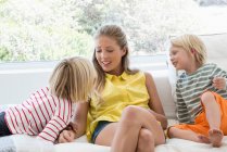 Счастливая мать и дети сидят на диване в гостиной — стоковое фото
