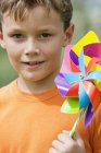 Portrait of little boy holding colorful pinwheel outdoors — Stock Photo