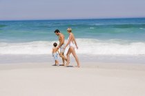 Счастливая семья гуляет по песчаному пляжу — стоковое фото