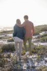 Romantisches Paar spaziert an der Küste mit Vegetation im Sonnenlicht — Stockfoto