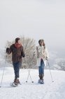 Молода пара катається на снігоступах в зимових горах — стокове фото