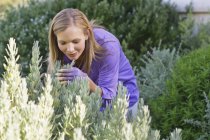 Young woman smelling flowers in summer garden — Stock Photo
