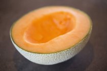 Gros plan de la moitié de melon frais sur fond brun — Photo de stock