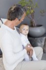 Pai com bebê bonito filha sentada em casa — Fotografia de Stock