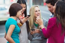 Friends using mobile phones outdoors — Stock Photo