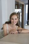 Портрет улыбающейся девочки-подростка, сидящей за столом — стоковое фото