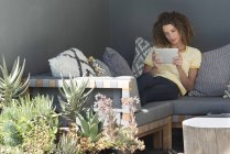 Frau sitzt zu Hause auf Couch und nutzt digitales Tablet — Stockfoto