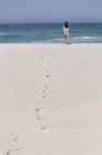 Вид ззаду розслабленої жінки, що стоїть на піщаному пляжі — стокове фото