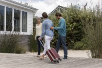 Glücklich reife Frau trifft junges Paar mit Gepäck im Freien — Stockfoto