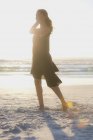 Чуттєва молода жінка стоїть на пляжі на сонячному світлі — стокове фото