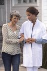 Enfermeira feminina assistindo sorridente mulher idosa em casa de repouso — Fotografia de Stock