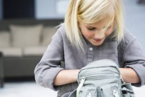 Little blond girl searching in bag — Stock Photo