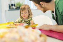Man and daughter having breakfast at table at home — Stock Photo