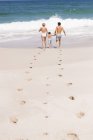 Footsteps on sandy beach with family on background — Stock Photo