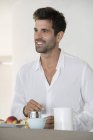 Щасливий чоловік насолоджується чашкою кави на кухні вдома — стокове фото