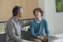 Vater spricht mit Sohn, der digitales Tablet im Wohnzimmer hält — Stockfoto