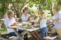 Mamma e bambini felici che mangiano nel cortile estivo — Foto stock