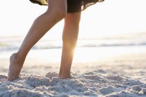 Frauenbeine stehen am Sandstrand im Sonnenlicht — Stockfoto