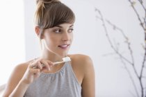 Крупным планом молодая женщина чистит зубы и смотрит в сторону — стоковое фото