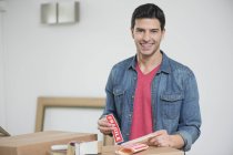 Man sticking Fragile sticker on cardboard boxes and looking at camera — Stock Photo