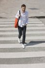 Selbstbewusster Mann mit Tasche läuft auf Zebrastreifen in der Stadt — Stockfoto