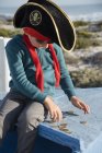 Menino pirata contando moedas em barco de madeira ao ar livre — Fotografia de Stock
