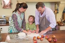 Милий маленький хлопчик і його батьки замішують тісто на кухні — стокове фото