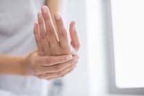 Primer plano de las manos femeninas aplicando crema hidratante en las manos - foto de stock