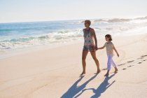 Mulher andando na praia com sua filha — Fotografia de Stock