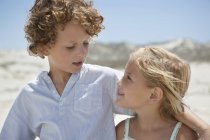 Close-up of brother and sister looking at each other on beach — Stock Photo