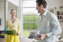 Couple carrying food and plates for serving at home — Stock Photo