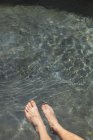 Gros plan des jambes humaines dans l'eau propre ondulation — Photo de stock