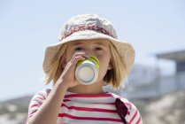Little girl in hat enjoying cold drink outdoors — Stock Photo
