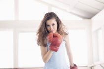Portrait of girl in boxing glove standing in room — Stock Photo