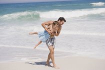Веселый мужчина играет с сыном на песчаном пляже — стоковое фото