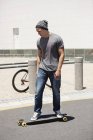 Hombre joven enfocado skateboarding en la carretera - foto de stock