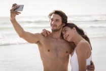 Pareja tomando selfie con teléfono móvil en la playa - foto de stock