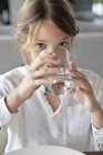 Portrait of little girl drinking water in kitchen — Stock Photo
