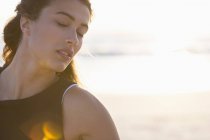 Чуттєва молода жінка з закритими очима позує на пляжі — стокове фото