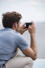 Молодий чоловік фотографує смартфон на відкритому повітрі — стокове фото