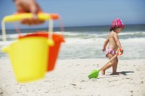 Bambina che cammina con la pala di sabbia sulla spiaggia di sabbia — Foto stock