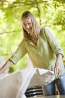 Smiling woman holding tablecloth in garden — Stock Photo