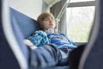 Adolescente durmiendo en sofá con auriculares - foto de stock