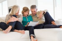 Junge mit digitalem Tablet bei seinen Großeltern auf der Couch — Stockfoto