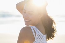 Щаслива молода жінка позує на пляжі на сонячному світлі — стокове фото