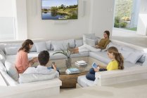 Familia multi-generación utilizando gadgets en la sala de estar - foto de stock