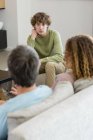 Family talking while sitting on sofa in living room at home — Stock Photo
