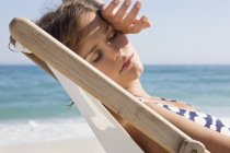 Primer plano de la mujer descansando en la tumbona en la playa - foto de stock