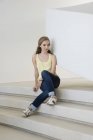 Menina adolescente pensativo sentado em passos e olhando para longe — Fotografia de Stock