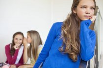 Nahaufnahme eines Teenagermädchens beim Denken mit Freundinnen, die im Hintergrund flüstern — Stockfoto